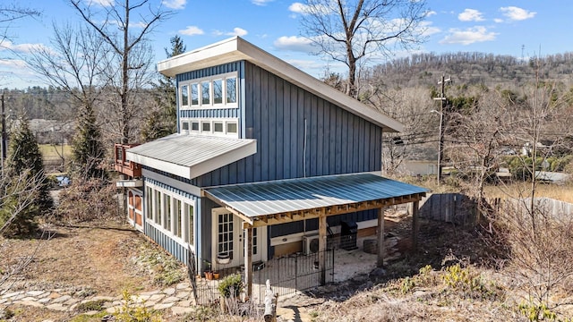 exterior space featuring board and batten siding, metal roof, and fence