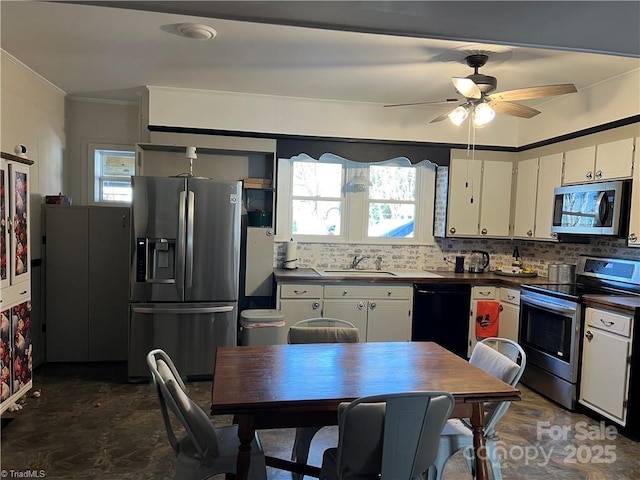 kitchen featuring a sink, white cabinets, appliances with stainless steel finishes, backsplash, and dark countertops