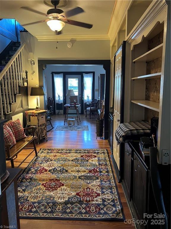 hall with stairs, crown molding, and wood finished floors