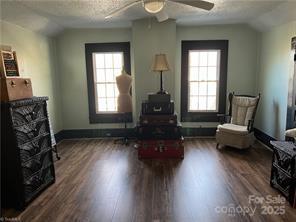 living area featuring lofted ceiling, dark wood finished floors, a textured ceiling, and baseboards