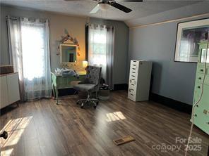 office area featuring dark wood-style floors, lofted ceiling, a ceiling fan, and radiator