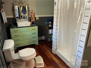 bathroom with a stall shower, toilet, and wood finished floors