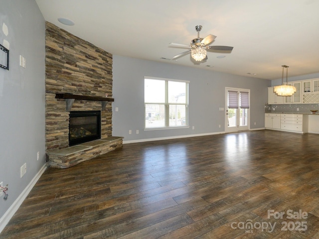 unfurnished living room with dark wood-type flooring, a fireplace, baseboards, and ceiling fan