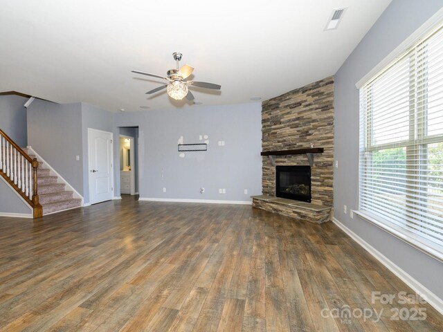 unfurnished living room featuring visible vents, wood finished floors, a fireplace, ceiling fan, and stairs