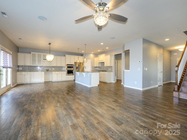 unfurnished living room with visible vents, baseboards, stairs, recessed lighting, and dark wood-style floors