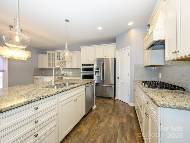 kitchen with custom range hood, a sink, dark wood-style floors, stainless steel appliances, and glass insert cabinets