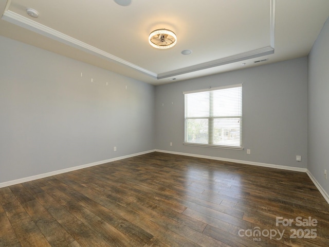 spare room with visible vents, a raised ceiling, dark wood-type flooring, and baseboards