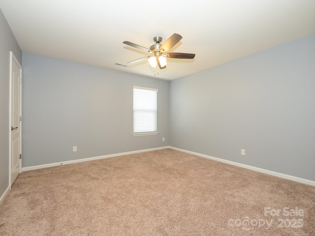 carpeted spare room featuring visible vents, baseboards, and ceiling fan