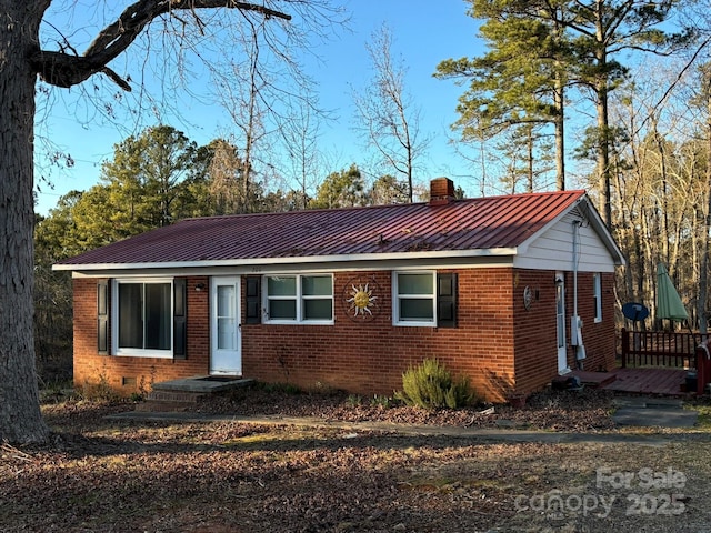 single story home featuring crawl space, brick siding, metal roof, and a chimney