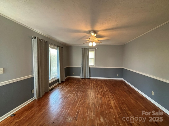 spare room featuring baseboards, dark wood finished floors, ceiling fan, ornamental molding, and a textured ceiling