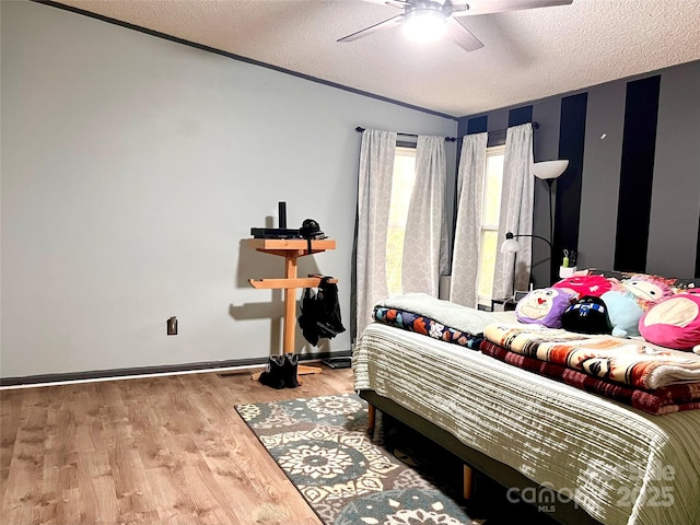 bedroom featuring a textured ceiling, ceiling fan, wood finished floors, and baseboards