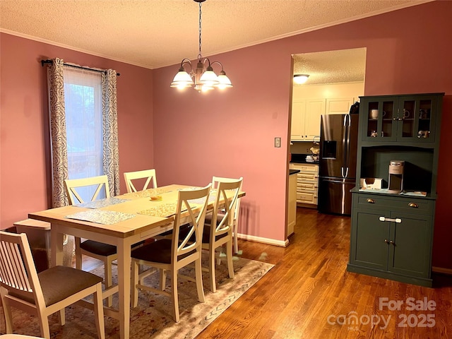 dining room with an inviting chandelier, crown molding, a textured ceiling, and wood finished floors