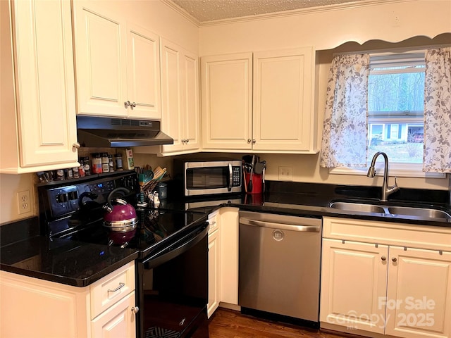 kitchen with stainless steel appliances, dark countertops, white cabinetry, a sink, and under cabinet range hood