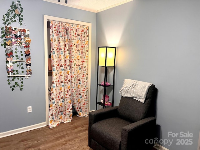 living area with crown molding, baseboards, and wood finished floors