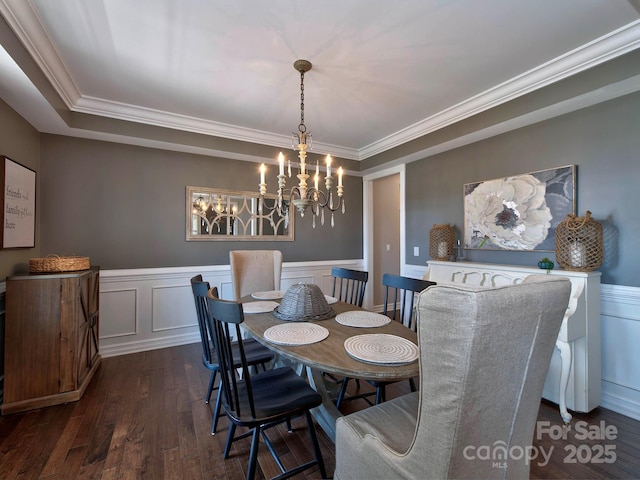 dining area with wainscoting, ornamental molding, dark wood-type flooring, a decorative wall, and a notable chandelier