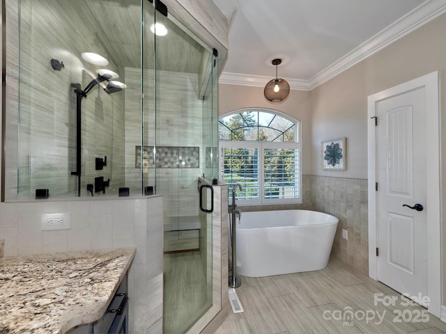 full bathroom featuring vanity, tile walls, a soaking tub, a stall shower, and crown molding