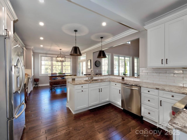 kitchen with a peninsula, stainless steel appliances, white cabinetry, pendant lighting, and a sink