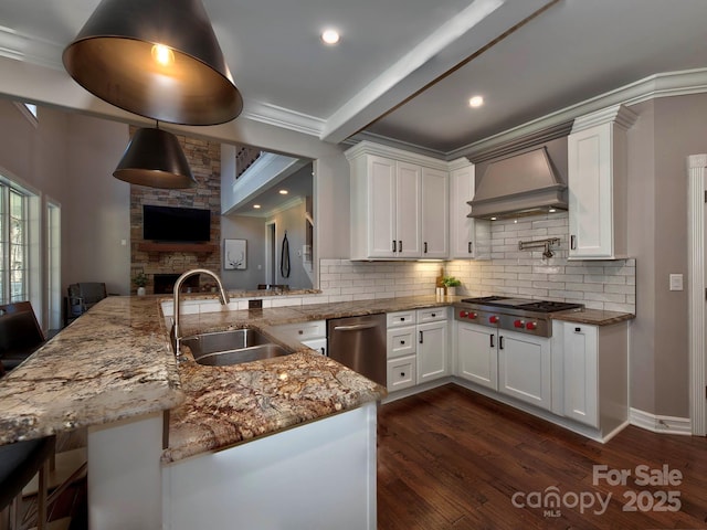 kitchen featuring a peninsula, premium range hood, white cabinetry, and a sink