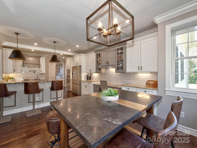 kitchen with glass insert cabinets, appliances with stainless steel finishes, a breakfast bar, white cabinetry, and pendant lighting