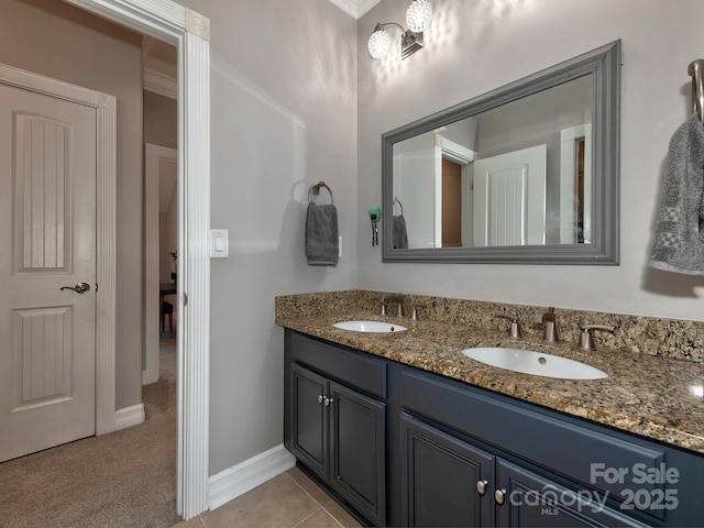 full bathroom with double vanity, baseboards, a sink, and tile patterned floors