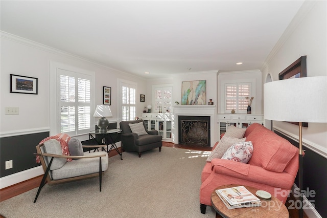 living area with a fireplace with flush hearth, baseboards, crown molding, and wood finished floors