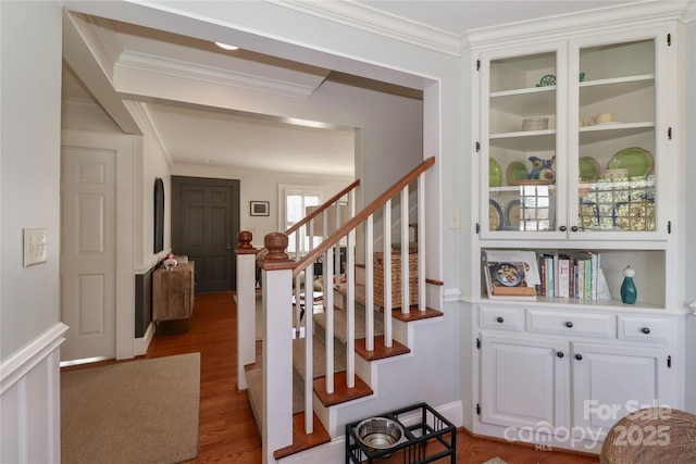 stairway with built in shelves, crown molding, and wood finished floors