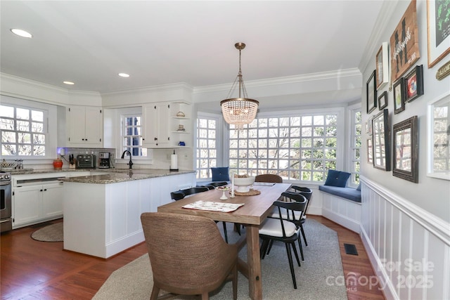 dining area with plenty of natural light, dark wood finished floors, visible vents, and crown molding