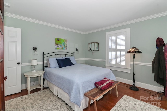 bedroom with ornamental molding, wood finished floors, and baseboards