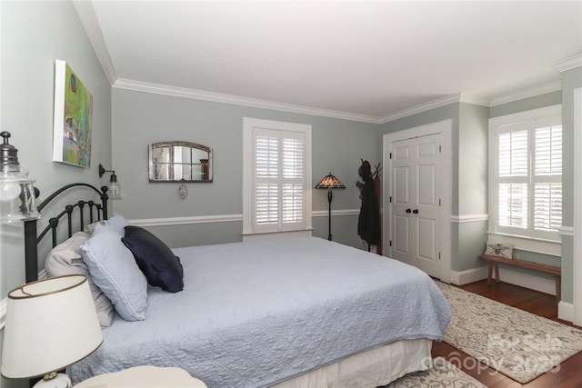 bedroom with ornamental molding, a closet, wood finished floors, and baseboards