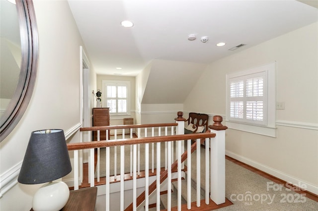 hallway with recessed lighting, wood finished floors, visible vents, baseboards, and an upstairs landing