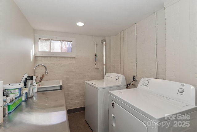 clothes washing area with laundry area, washing machine and dryer, and a sink