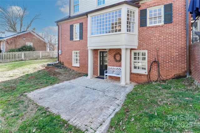 exterior space featuring brick siding, fence, and a front lawn