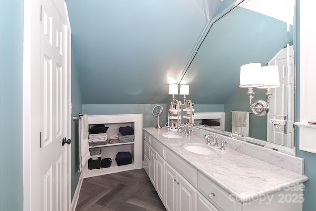 bathroom featuring lofted ceiling, a sink, and double vanity