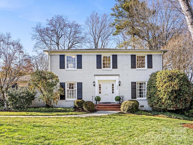 colonial home with a front lawn and brick siding