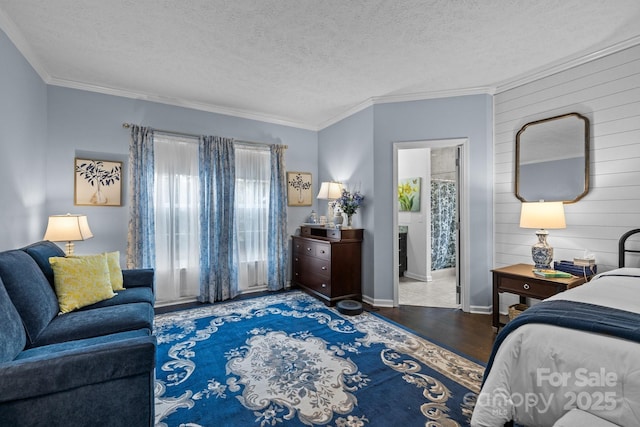 bedroom featuring ornamental molding, ensuite bathroom, a textured ceiling, wood finished floors, and baseboards