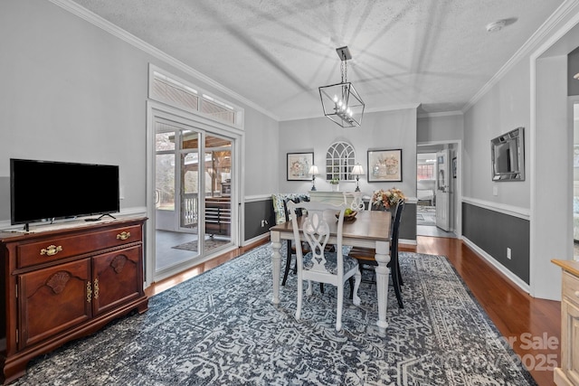 dining room with an inviting chandelier, crown molding, dark wood-style flooring, and a textured ceiling