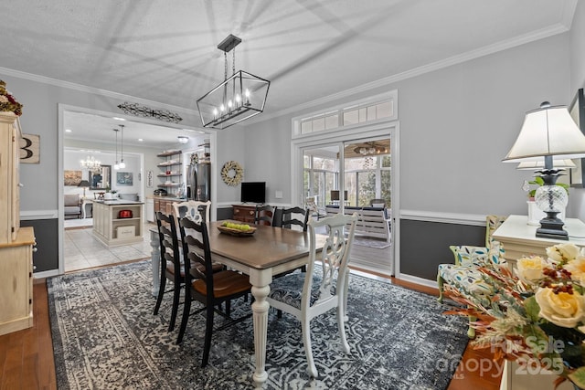 dining space with an inviting chandelier, wood finished floors, and crown molding