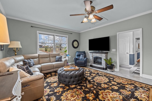 living area with a stone fireplace, crown molding, a ceiling fan, and baseboards