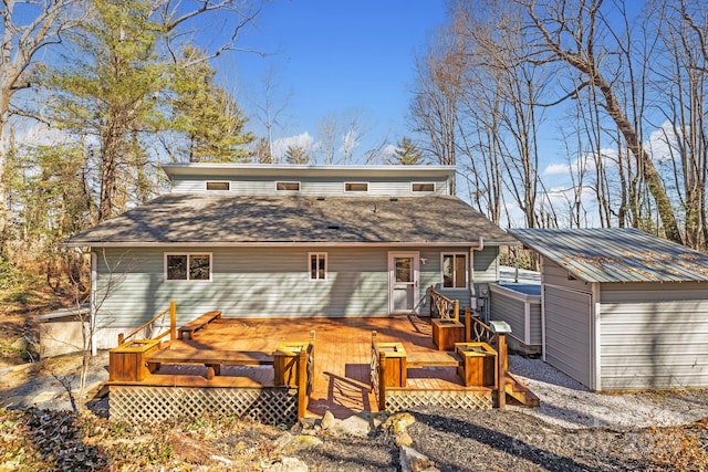 rear view of property featuring a jacuzzi and a deck