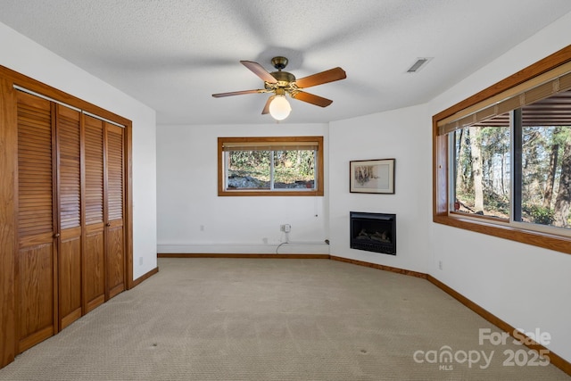 unfurnished living room featuring a healthy amount of sunlight, a fireplace, visible vents, and light carpet