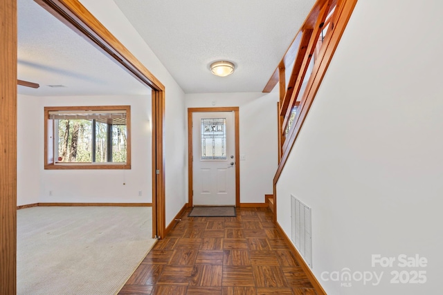 doorway featuring stairway, baseboards, visible vents, and a textured ceiling