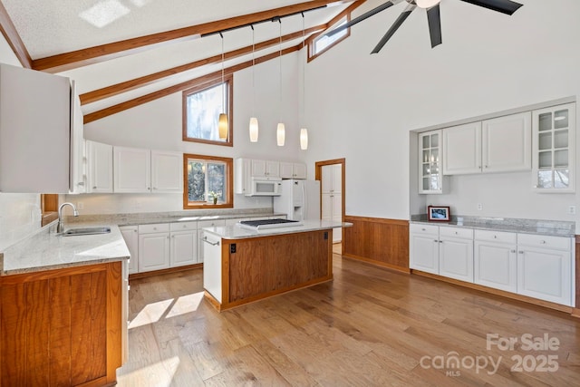 kitchen with white appliances, glass insert cabinets, a center island, white cabinetry, and a sink