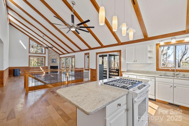 kitchen featuring a center island, open floor plan, white cabinetry, a sink, and white appliances