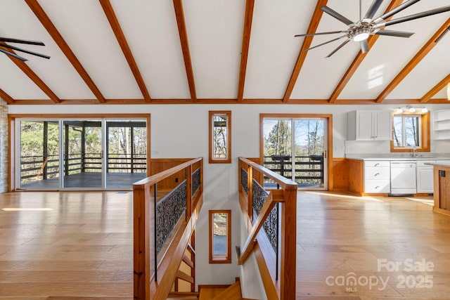 hallway with light wood finished floors, a wealth of natural light, lofted ceiling with beams, and an upstairs landing