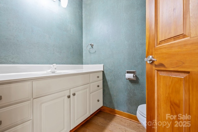 bathroom featuring vanity, toilet, and wood finished floors