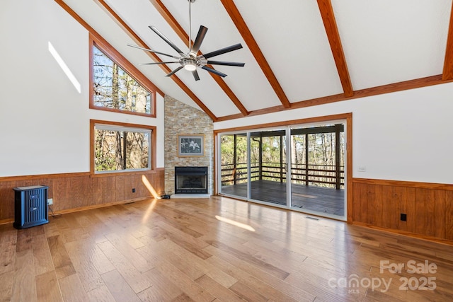 unfurnished living room featuring a wainscoted wall, plenty of natural light, and beam ceiling