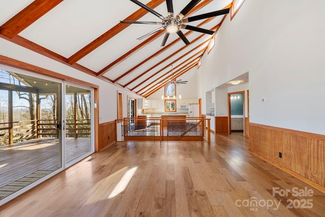 interior space with high vaulted ceiling, light wood-style flooring, a ceiling fan, wainscoting, and beamed ceiling