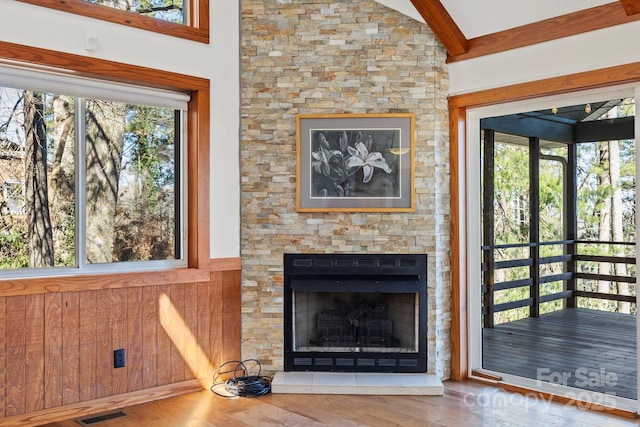 unfurnished living room featuring visible vents, lofted ceiling with beams, wood finished floors, and a wealth of natural light