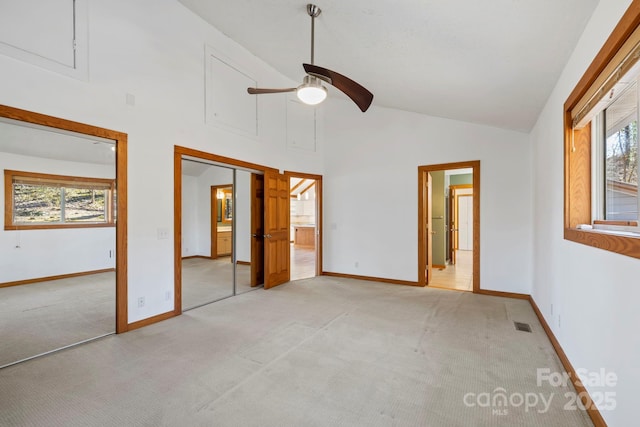 unfurnished bedroom featuring high vaulted ceiling, light colored carpet, and multiple windows