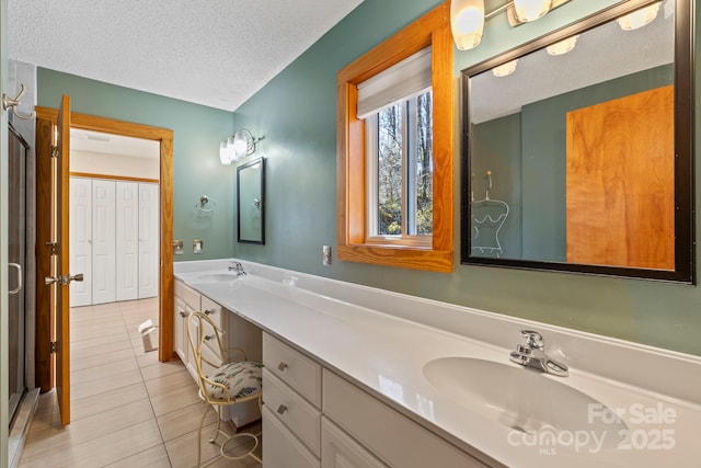 full bath with double vanity, a textured ceiling, a sink, and tile patterned floors